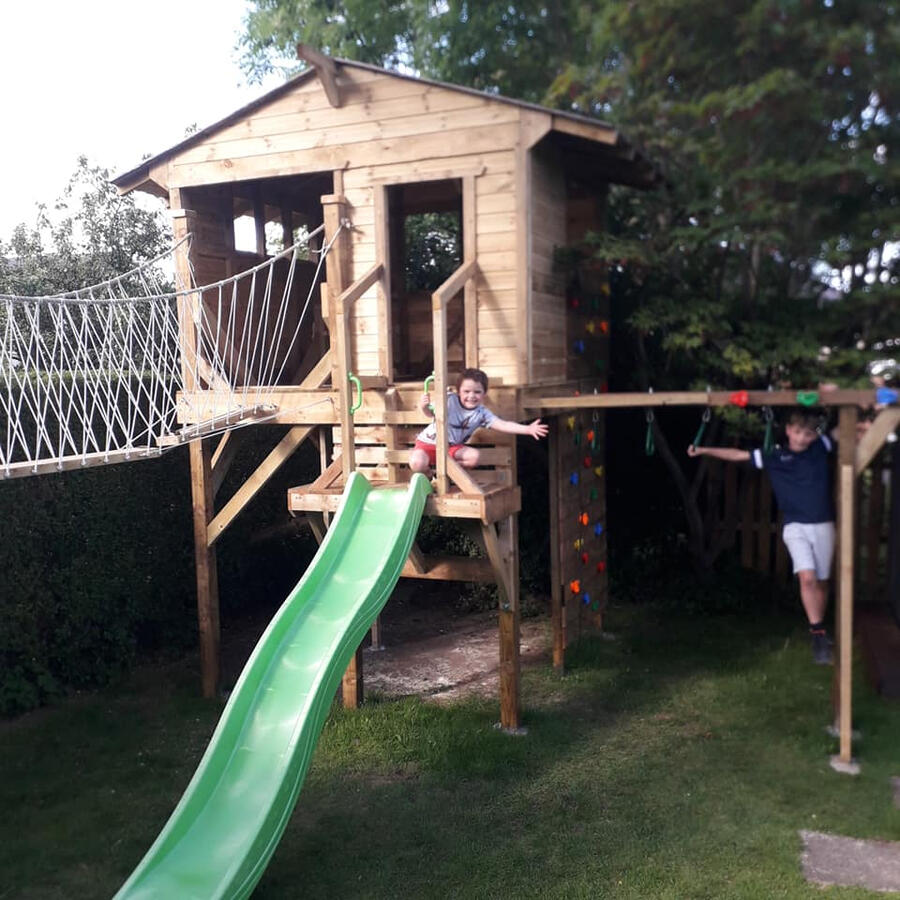 Stilted treehouse with rope bridge, swing and monkey bars